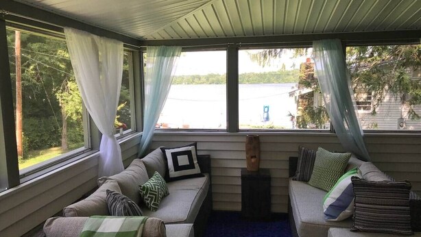 Een knus ingerichte kamer met een zithoek, een tafeltje en uitzicht op een meer.
