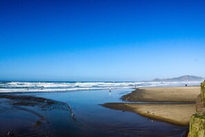 Una playa con olas, una orilla arenosa y una montaña a lo lejos.