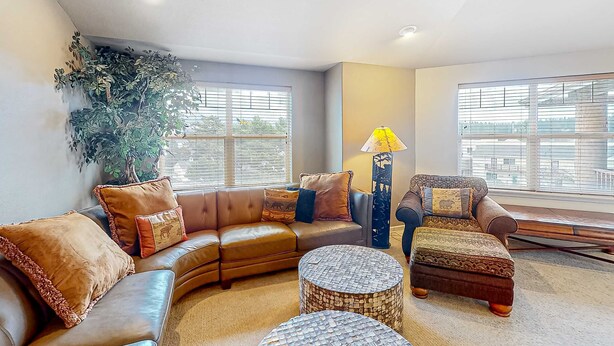 A living room with a sectional sofa, a round coffee table, and a patterned ottoman. - Classy and Convenient Dog-Friendly Condo with Private Balcony (Florence)