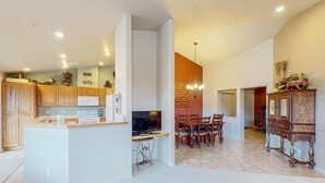 A modern kitchen with wooden cabinets, a dining area with a chandelier, and a large wooden cabinet. - Classy and Convenient Dog-Friendly Condo with Private Balcony (Florence)