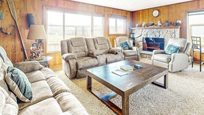 A living room with a fireplace, a sofa, a coffee table, and a television. - Dog-friendly oceanfront beach home with private hot tub and stunning ocean views (Yachats)