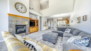 A spacious living room with a fireplace, grey sofas, and a television. - Two-Story Townhouse withFree WiFi, Fireplace, AC, Patio, & Shared Hot Tub, Pools (Eagle Crest)