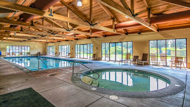 An indoor swimming pool with a wooden ceiling and large windows. - Two-Story Townhouse withFree WiFi, Fireplace, AC, Patio, & Shared Hot Tub, Pools (Eagle Crest)