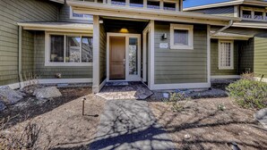 A two-story house with a front porch, a number '1258' on the door, and a small garden area with rocks and plants. - Two-Story Townhouse withFree WiFi, Fireplace, AC, Patio, & Shared Hot Tub, Pools (Eagle Crest)