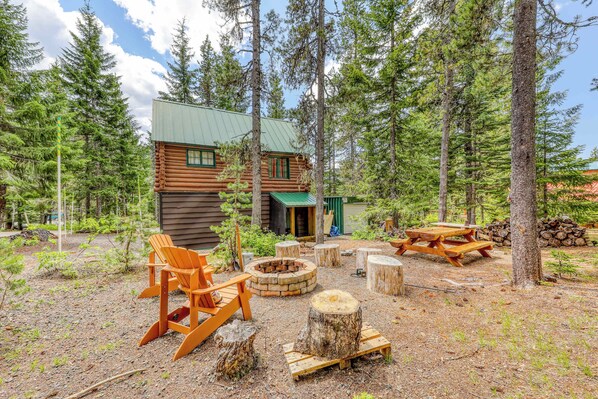 A log cabin with a deck, a fire pit, and a picnic table in a forest setting. - Adorable studio with modern amenities - close to slopes & restaurants (Government Camp)
