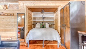 Ein Holzblockhaus-Interieur mit einem Bett, einem kleinen Tisch und einem Kamin.