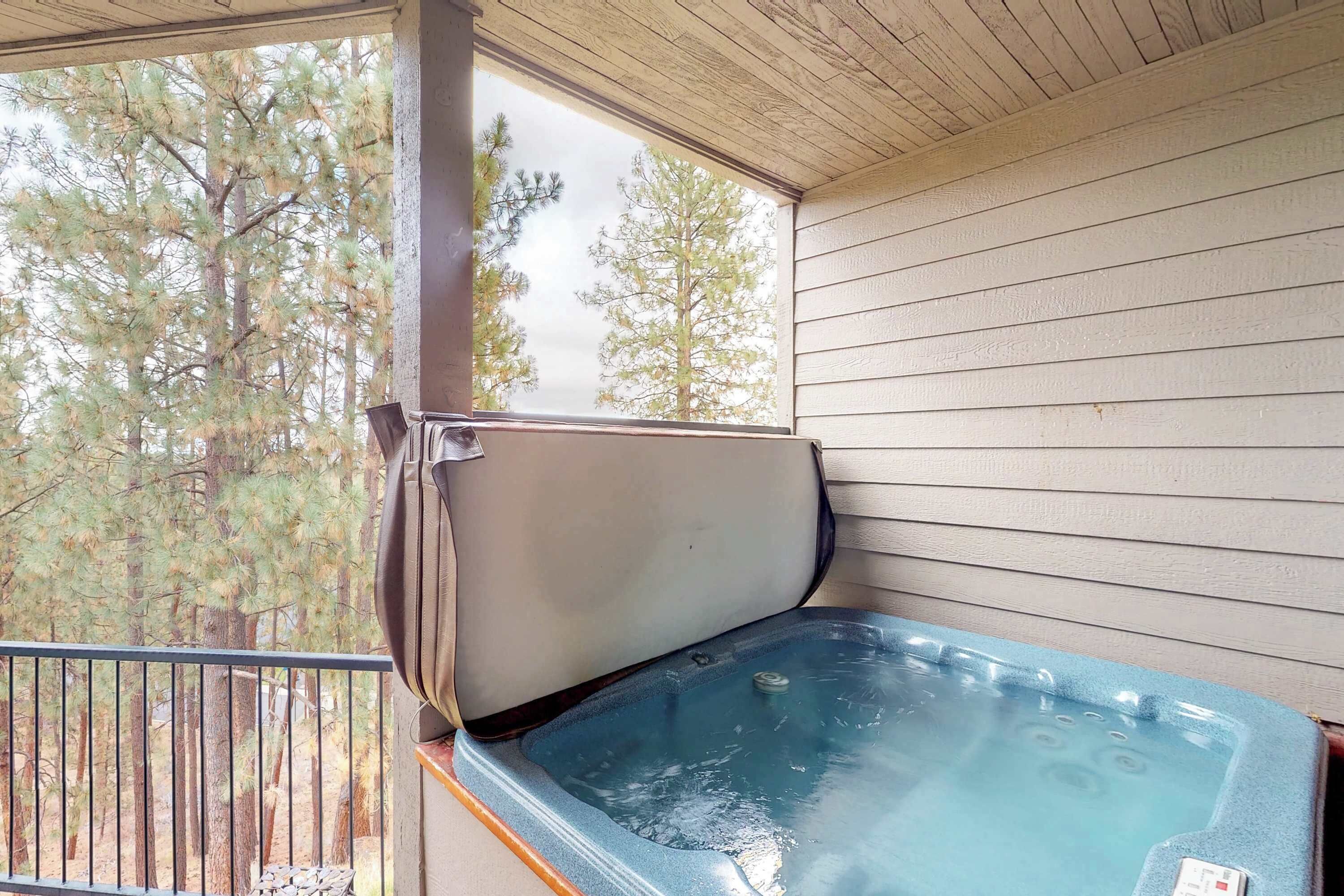 A hot tub on a balcony with a view of trees.