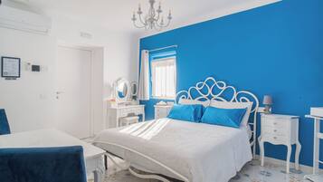 A bedroom with a bed, bedside tables, a dresser, a chair, and a chandelier.