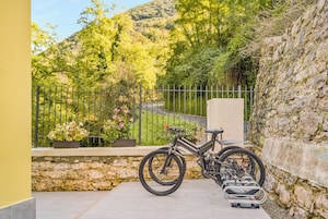 Una bicicleta estacionada frente a un muro de piedra, con vistas a una montaña y vegetación.