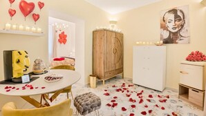 Ein Zimmer mit einem Esstisch, einer Holzkommode, einem weißen Kühlschrank und einem Bild an der Wand.