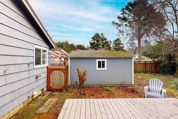 Un jardin avec un abri de jardin, une terrasse en bois et une chaise blanche.