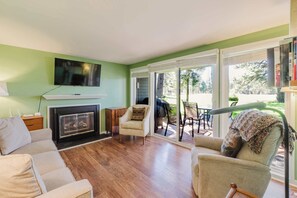 A living room with a fireplace, a television, and a view of the outdoors. - Dog-friendly condo with 6 SHARC passes & great golf course views (Sunriver)
