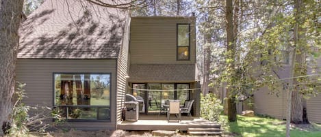 A modern house with a patio, a grill, and a large window overlooking the yard.