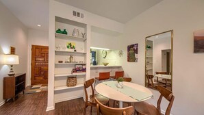 Un coin repas avec une table ronde, des chaises en bois et des étagères remplies de divers objets.