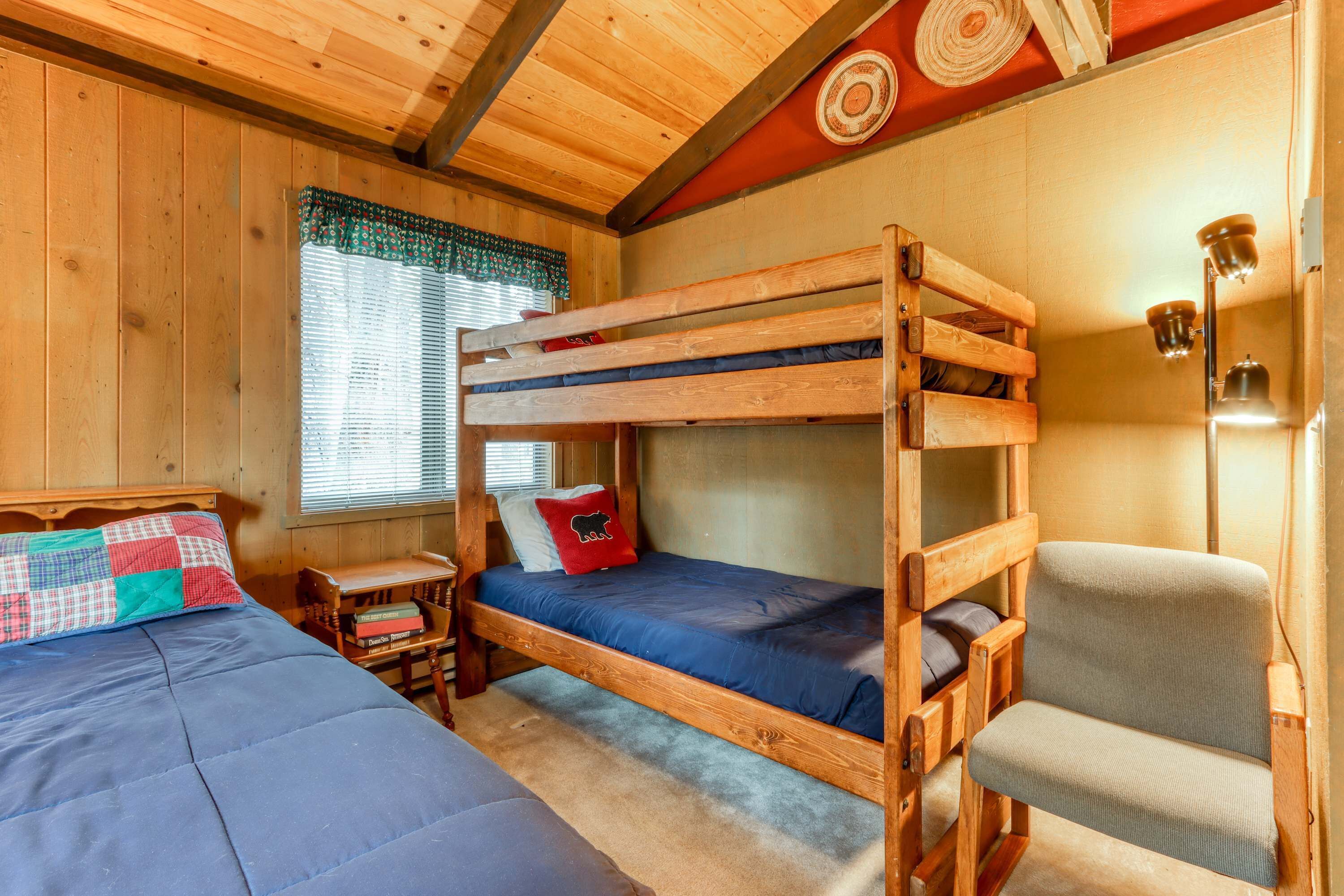 Camera con letto a castello, soffitto in legno, un tavolino e una sedia.