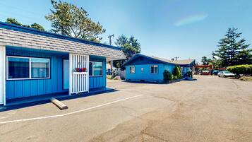 Ein Motel mit zwei blauen Gebäuden, einem Parkplatz und wolkenlosem Himmel.