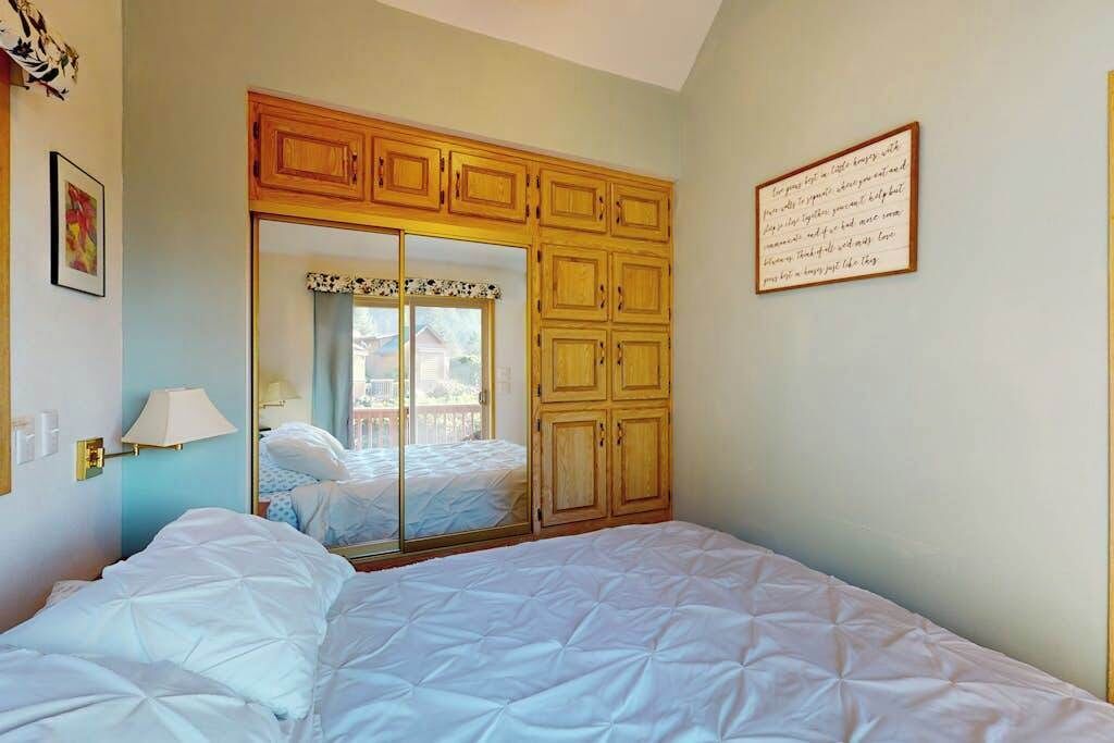 A bedroom with a bed, a wardrobe, a mirror, and a framed note on the wall.