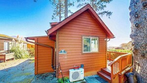 A small wooden cabin with a porch, a window, and an air conditioning unit. - Dog-friendly cabin withprivate hot tub, large deck & beautiful ocean mountain view (Brookings)