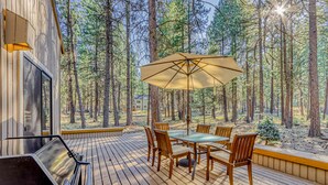 Une terrasse équipée d’un barbecue, d’une table, de chaises et d’un parasol.