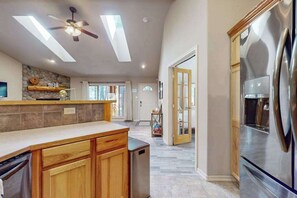 A modern kitchen with a built-in refrigerator, wooden cabinets, and a ceiling fan. - Charming home in wooded setting with deck, BBQ grill, WiFi, and fireplace (Sunriver)