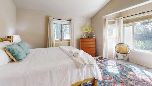 Un dormitorio con cama, cómoda, silla y ventana.