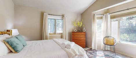 A bedroom with a bed, a dresser, a chair, and a window.