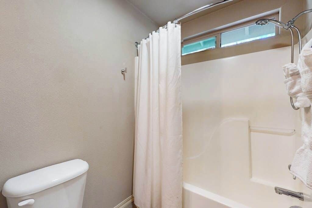 Une salle de bain comprenant des toilettes, une douche avec un rideau et une baignoire.