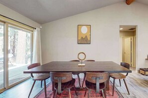 A dining area with a large table, six chairs, and a rug. - Charming home in wooded setting with deck, BBQ grill, WiFi, and fireplace (Sunriver)