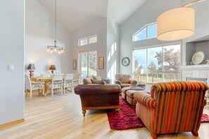 A spacious living room with a dining area, large windows, and a fireplace.
