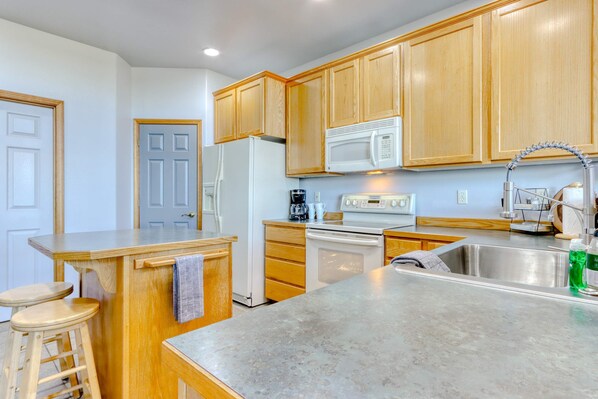 A kitchen with wooden cabinets, a refrigerator, a microwave, a stove, and a sink. - Golf course-front home with deck, hot tub, fireplace, W&D, & community pool (Eagle Crest)
