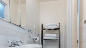 A bathroom with a wooden vanity, a white sink, a mirror, a toilet, and a towel rack.