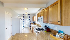 A kitchen with granite countertops, wooden cabinets, a gas stove, and a microwave. - Dog-Friendly Home w/ Gas Fireplace & Patio, in a Great Location Near the Beach (Newport)
