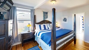A bedroom with a four-poster bed, a desk with a lamp, a television, and a view of the outside. - Dog-Friendly Home w/ Gas Fireplace & Patio, in a Great Location Near the Beach (Newport)
