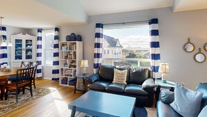 A living room with a dining area, a sofa, a coffee table, and a bookshelf. - Dog-Friendly Home w/ Gas Fireplace & Patio, in a Great Location Near the Beach (Newport)