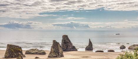 A coastal landscape with large rock formations and a beach.