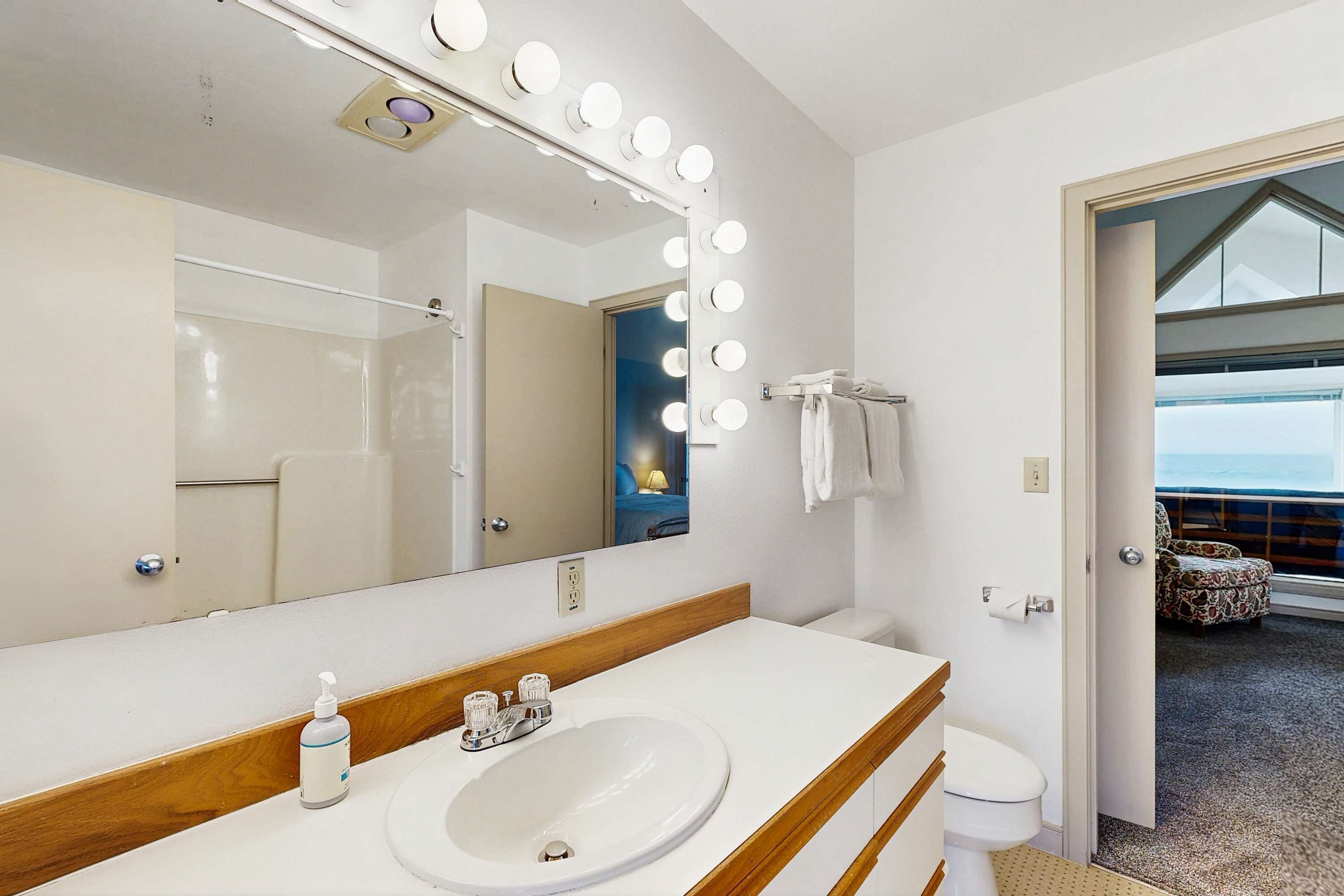 A bathroom with a large mirror, vanity, and lights.
