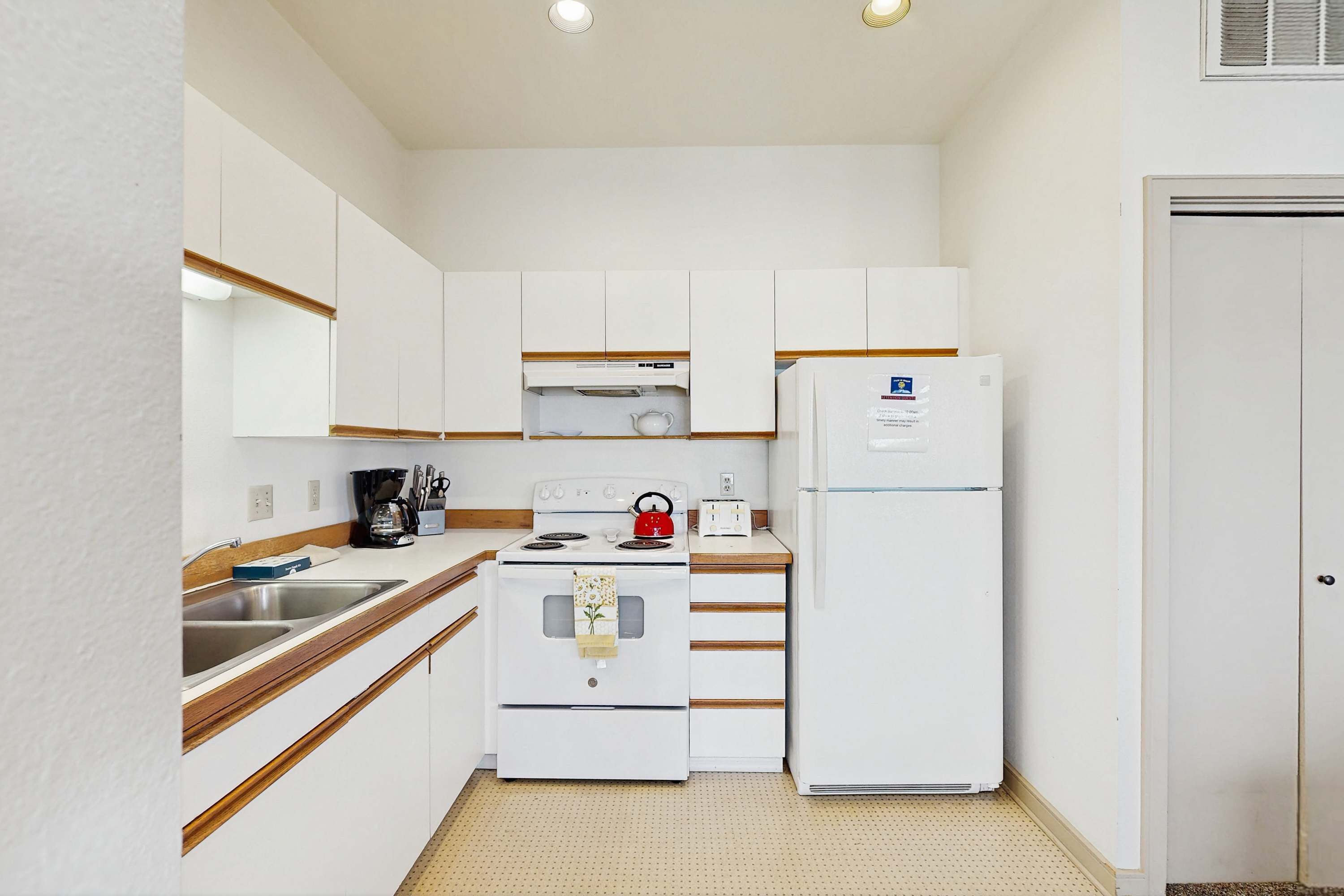 A compact kitchen with white appliances, a sink, and wooden countertops.