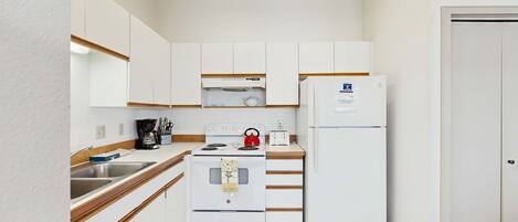 A compact kitchen with white appliances, a sink, and wooden countertops.