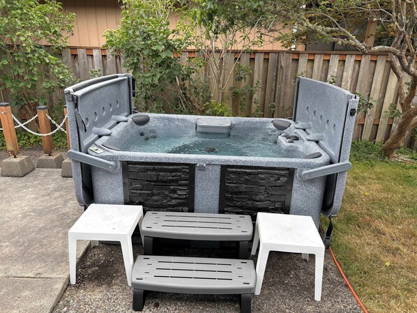 Een hottub met twee witte plastic stoelen en een kleine tafel ervoor.
