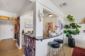 Una cocina moderna con barra, muebles de cocina blancos, una decoración de cráneo de toro y una gran planta en maceta.