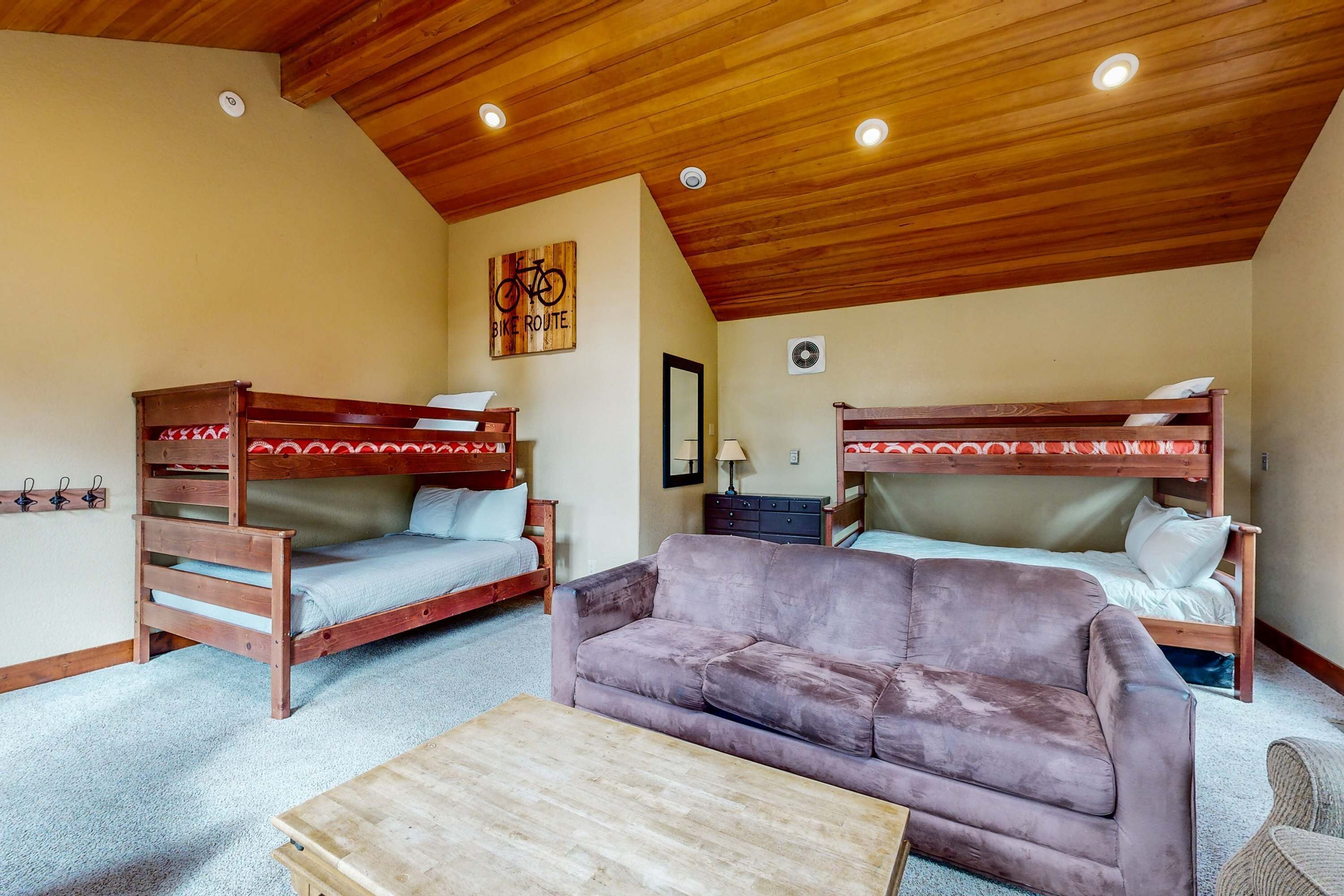 Ein Zimmer mit zwei Etagenbetten, einer Schlafcouch und einem Holztisch.