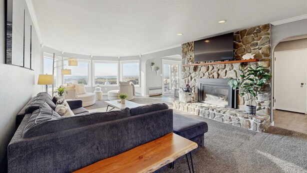 A modern living room with a stone fireplace, a large flat-screen TV, and a sofa.