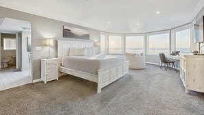 A bedroom with a large bed, a desk, and a view of the city.