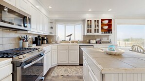 A modern kitchen with white cabinetry, a built-in oven, and a large island with a bowl.
