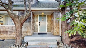 A house with a front door, steps, and a tree in the foreground.