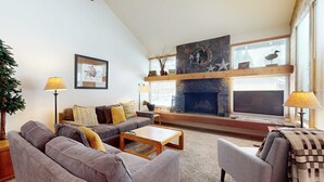 A modern living room with a fireplace, sofas, a coffee table, and decorative items. - Open & modern condo with pool, hot tub, fireplace & W&D (Sunriver)