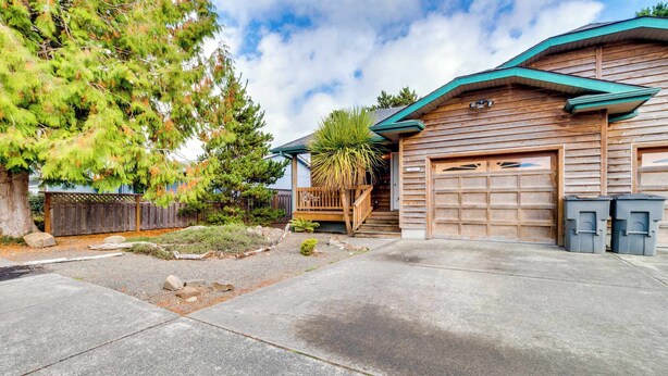 A two-story house with a garage, a wooden deck, and a small garden area. - Dog-Friendly, Coastal Escape with Private Hot Tub, WiFi, & Deck - Blocks to Park (Seaside)
