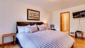 A bedroom with a bed, a nightstand, a television, and a painting on the wall. - Dog-Friendly, Coastal Escape with Private Hot Tub, WiFi, & Deck - Blocks to Park (Seaside)