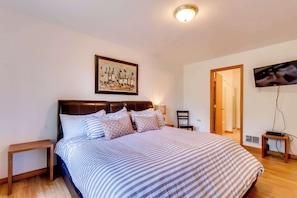 A bedroom with a bed, a nightstand, a television, and a painting on the wall. - Dog-Friendly, Coastal Escape with Private Hot Tub, WiFi, & Deck - Blocks to Park (Seaside)