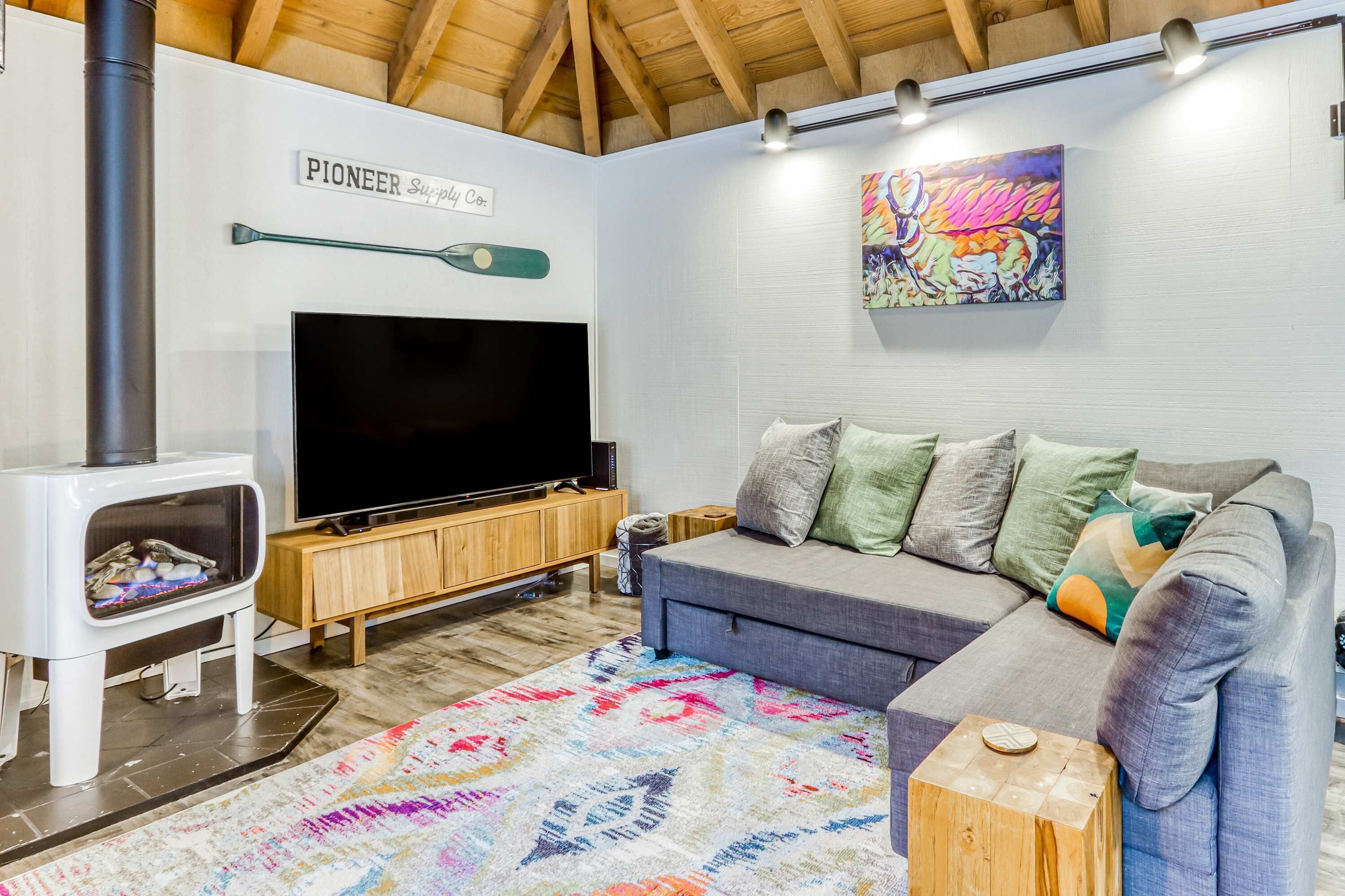 Una sala de estar con televisión, sofá, alfombra colorida y chimenea.